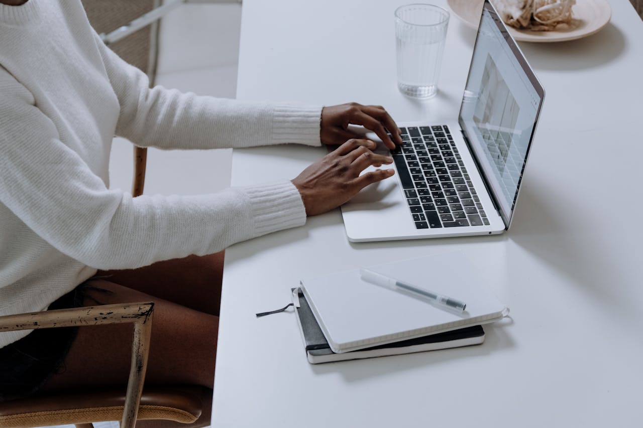 Home A person typing on a laptop in a minimalistic home office setting, capturing modern work culture.